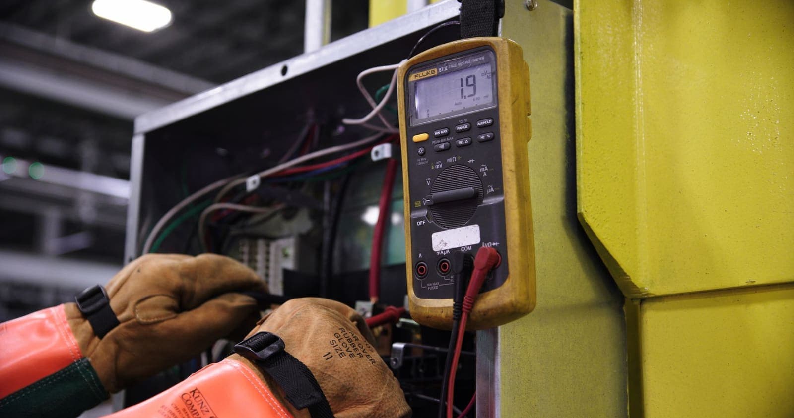 Electrician servicing an electrical distribution panel during MEP maintenance
